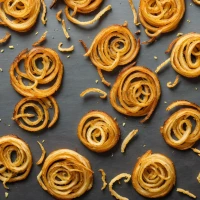 Crispy fried onion strings on wooden board for snacking. Crispy fried onion strings on wooden board for snacking.