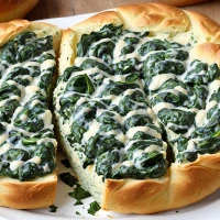 Spinach dip in bread bowl on table for tasty appetizer.