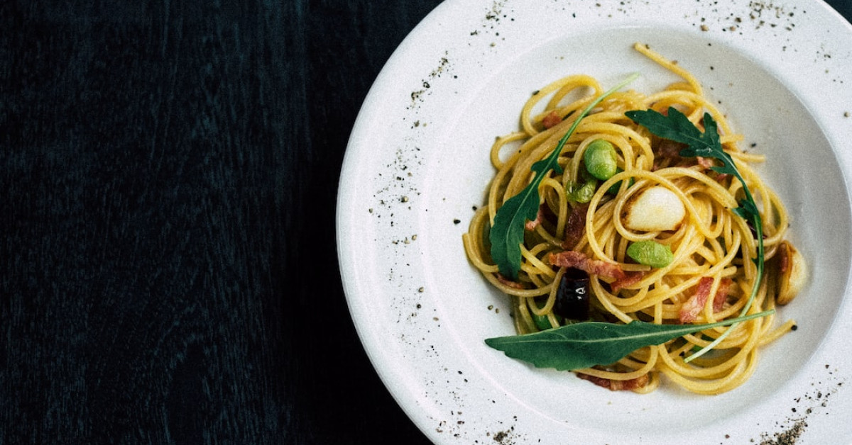 Gourmet bacon pasta with vegetables on plate.