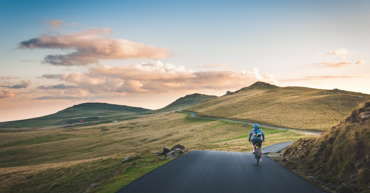 Cyclist on road demonstrating weight loss through biking exercise.
