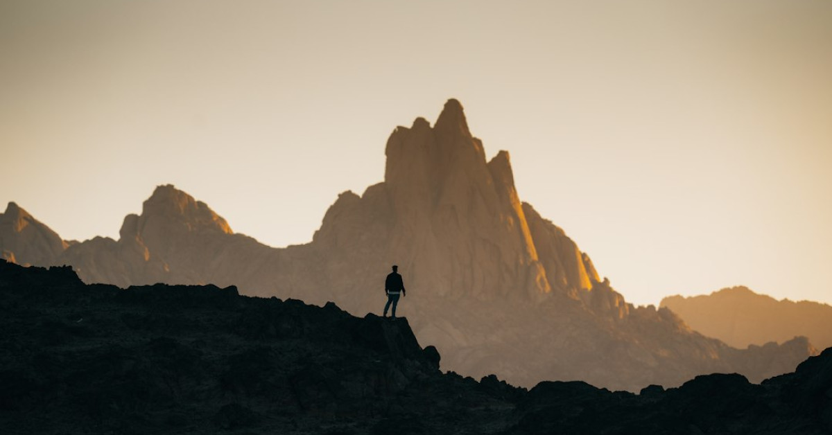 Hikers' silhouette at twilight on mountain trekking adventure.
