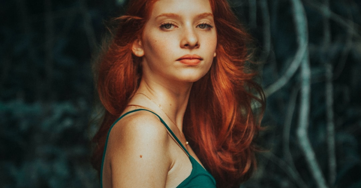 Redheaded hiker triumphs in trek wearing red hiking boots.